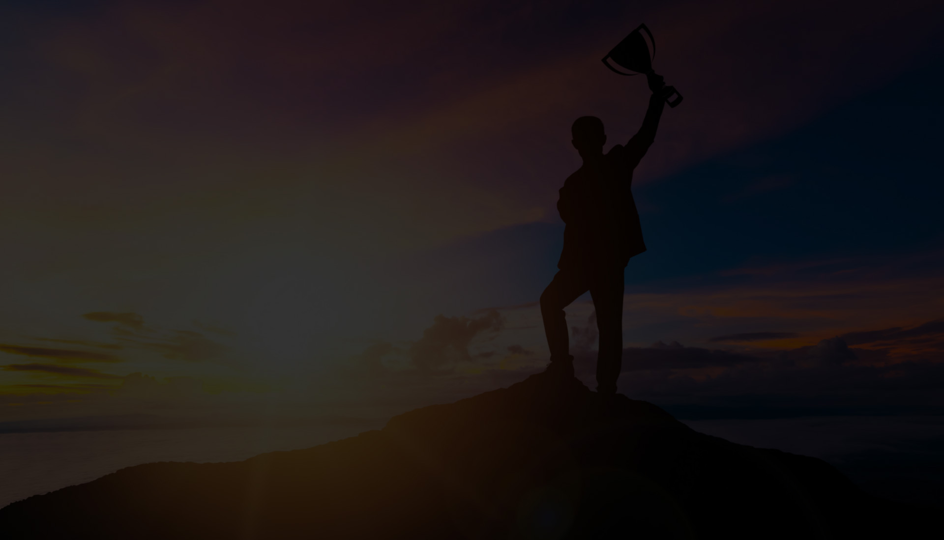 man holding trophy aloft on a mountain top
